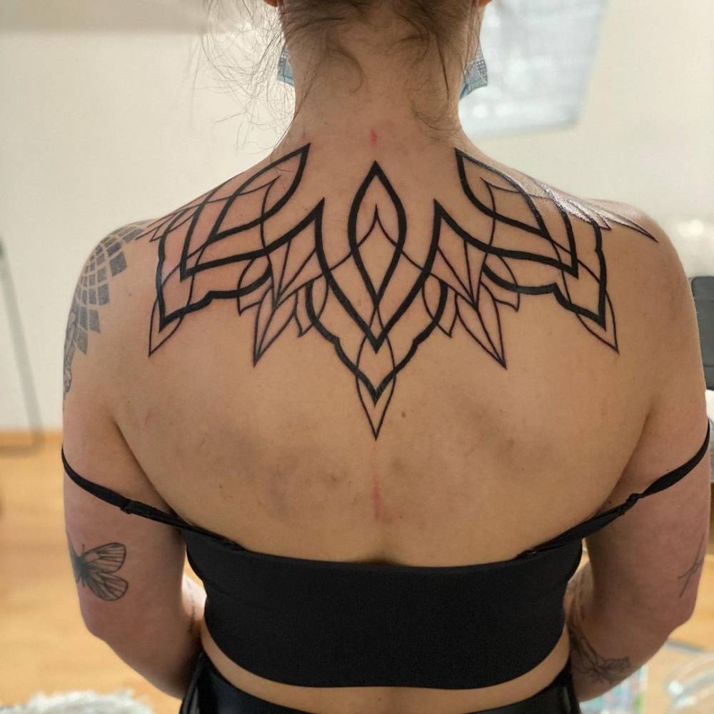 Line art lotus flower tattoo on the upper back.