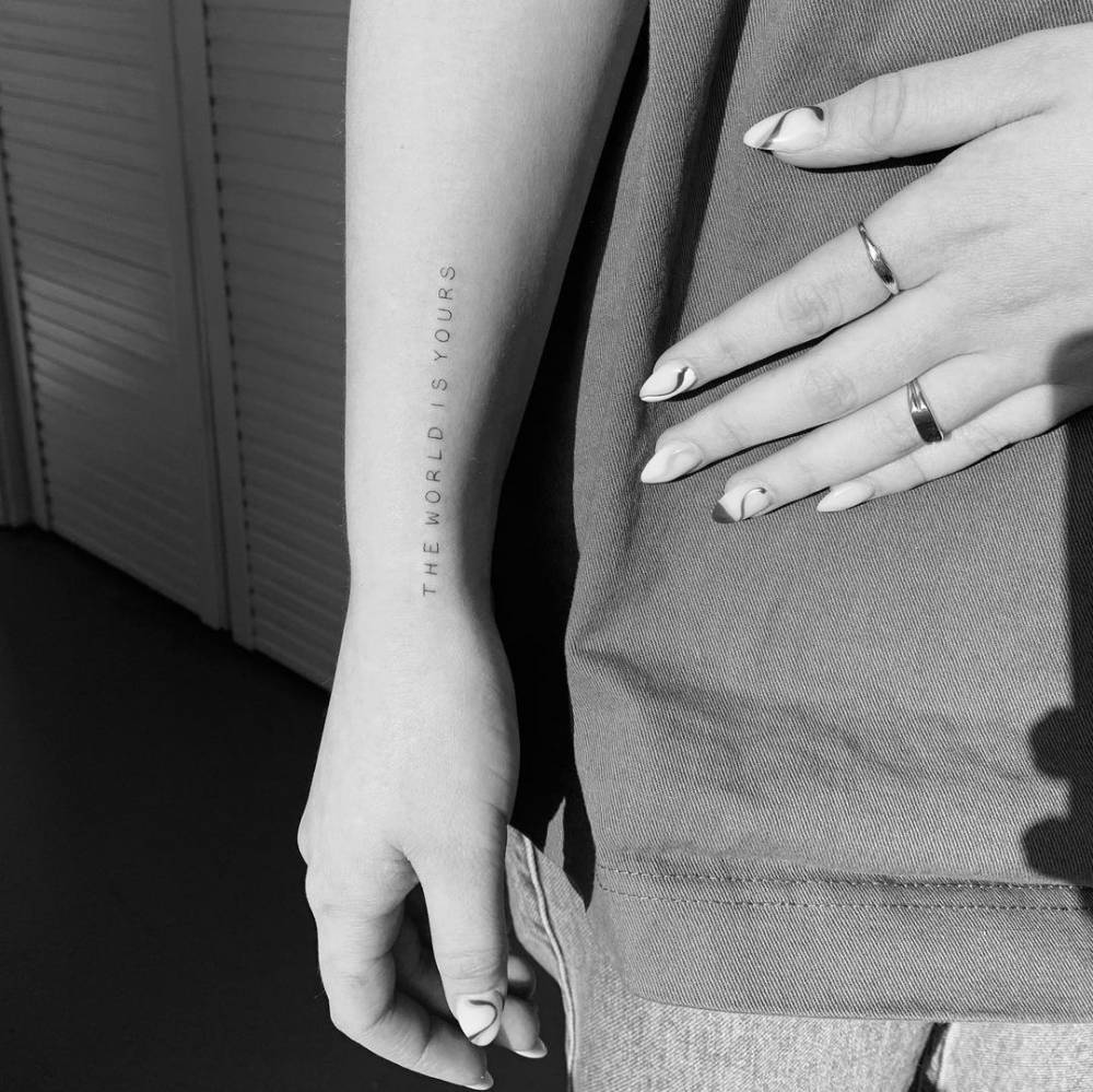 "The world is yours" lettering tattoo on the wrist.