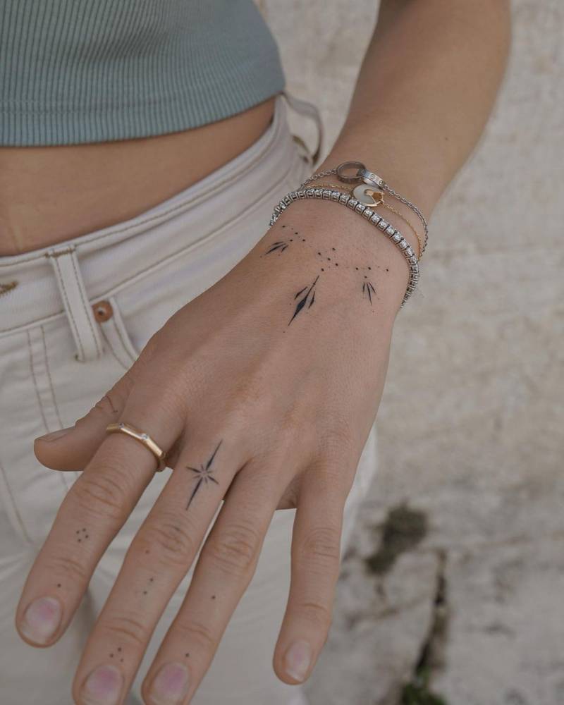 Hand poked north star and ornaments tattoo on the hand.
