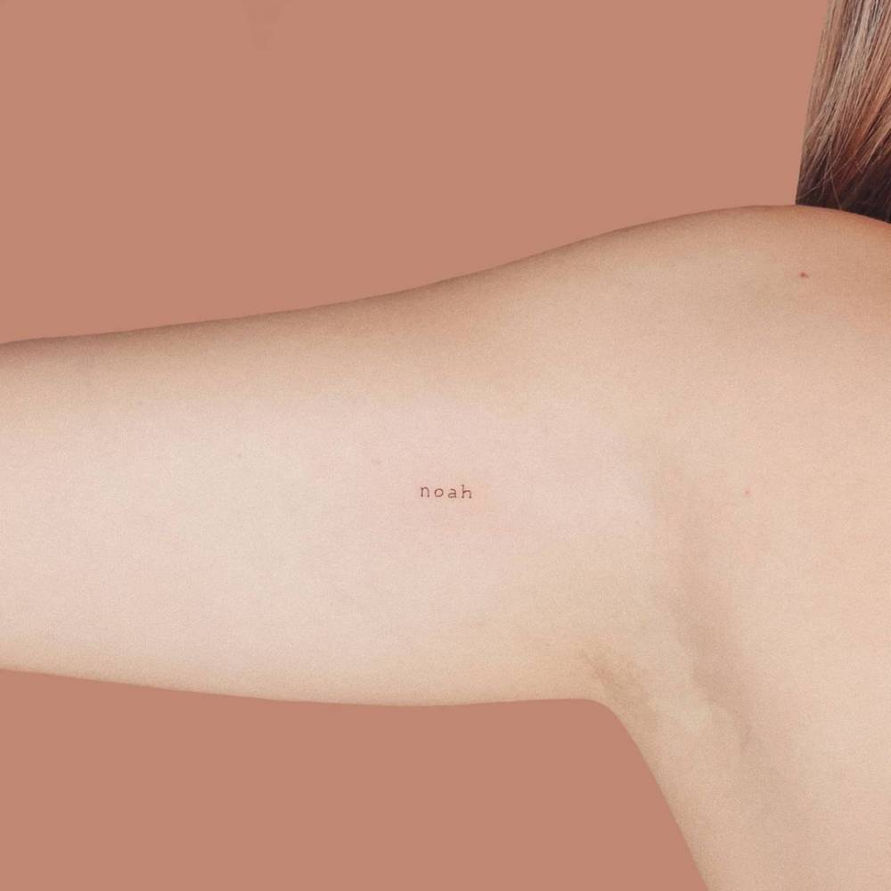 "Noah" lettering tattoo on the inner arm.