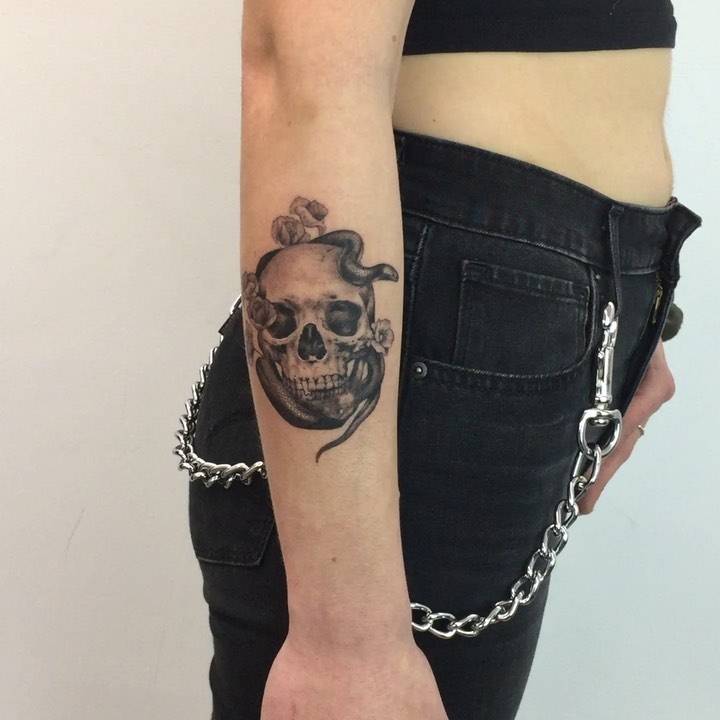 Micro-realistic skull and snake portrait tattoo on the forearm.