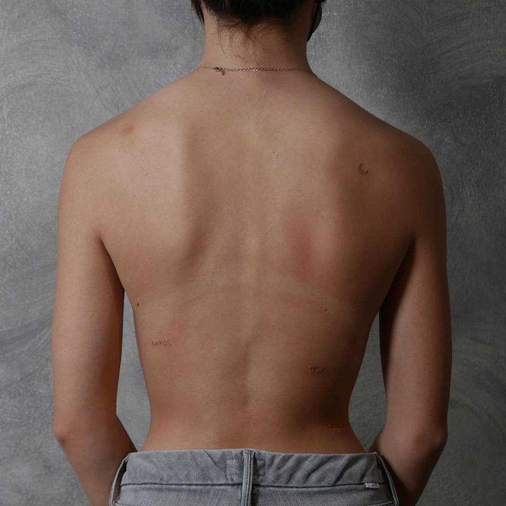 Single needle crescent moon, kanji and word tattoos on the back.