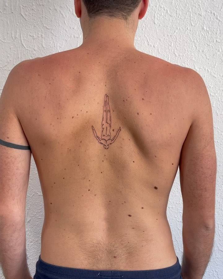 Fine line diver tattoo on the upper back.