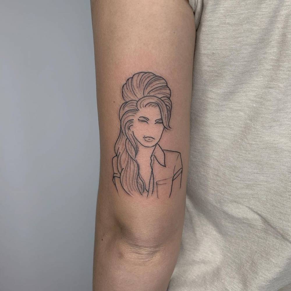 Line art Amy Winehouse portrait tattoo on the tricep.