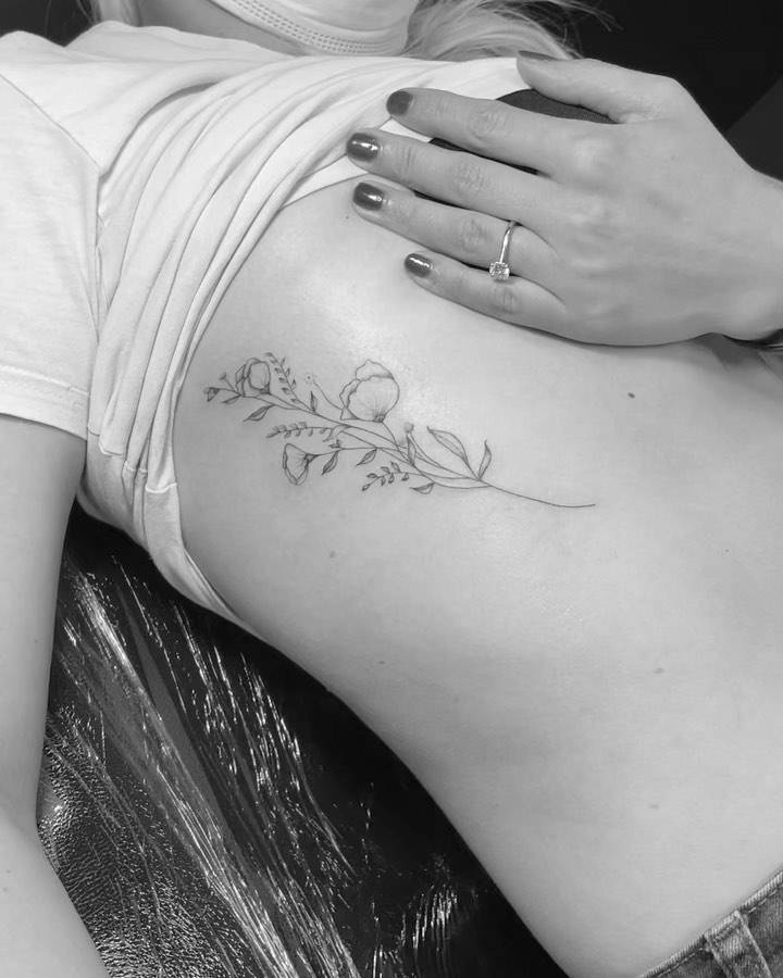 Fine line flowers tattoo on the rib.