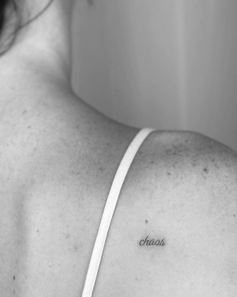 "Chaos" lettering tattoo on the shoulder blade.