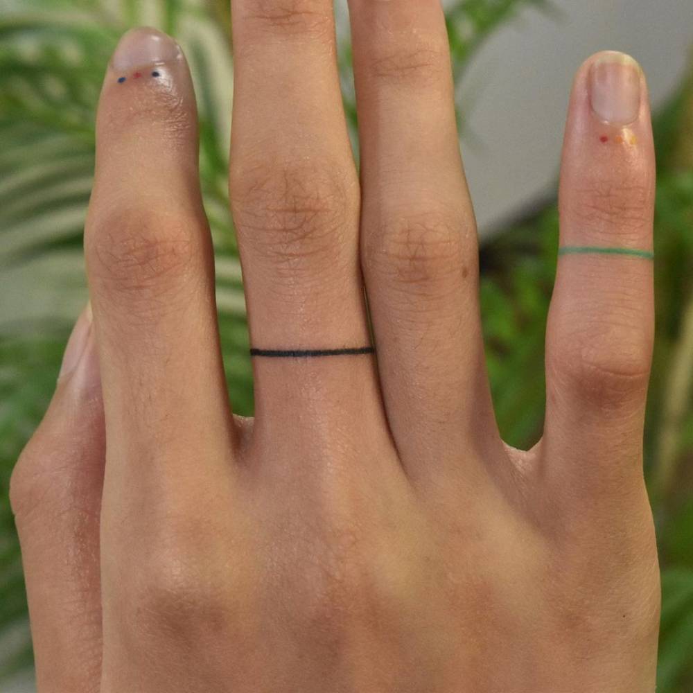 Minimalist rings and dots tattoo on the fingers.