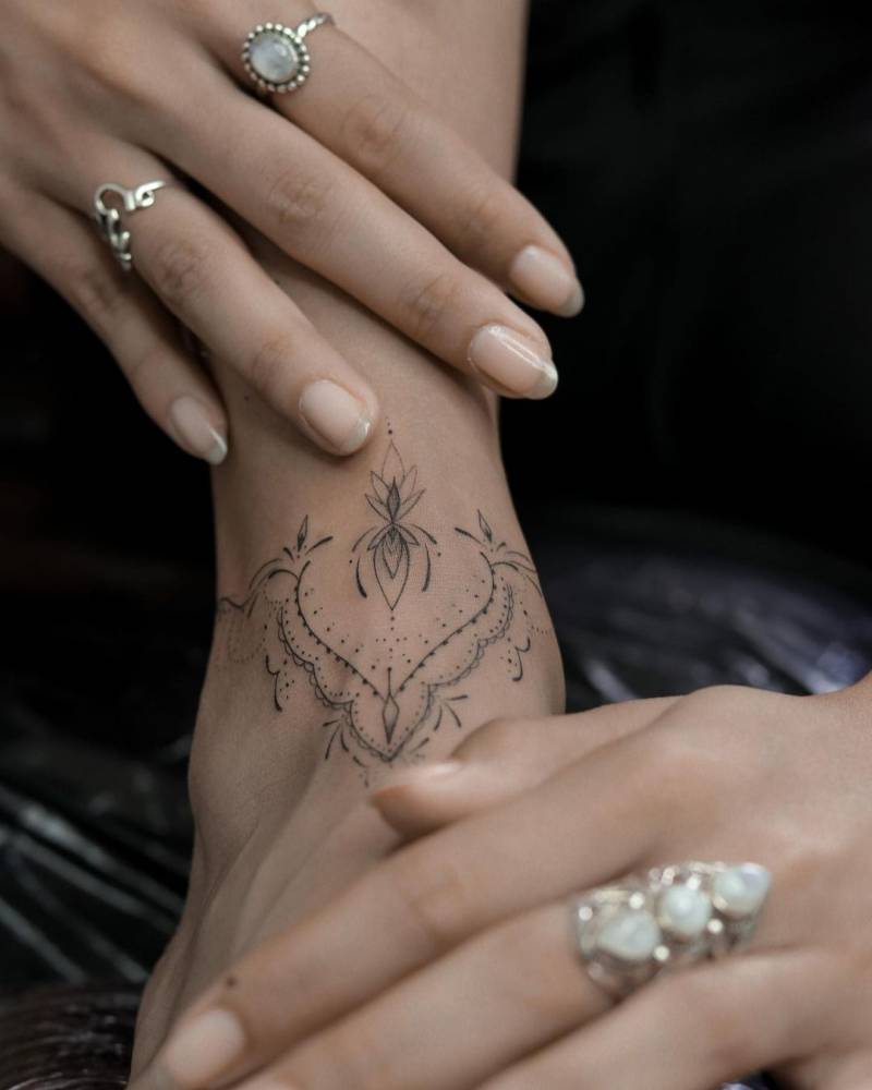 Fine line ornamental tattoo on the ankle.