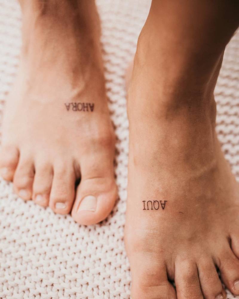 "Aquí" and "Ahora" individual matching lettering tattoo on the foot.