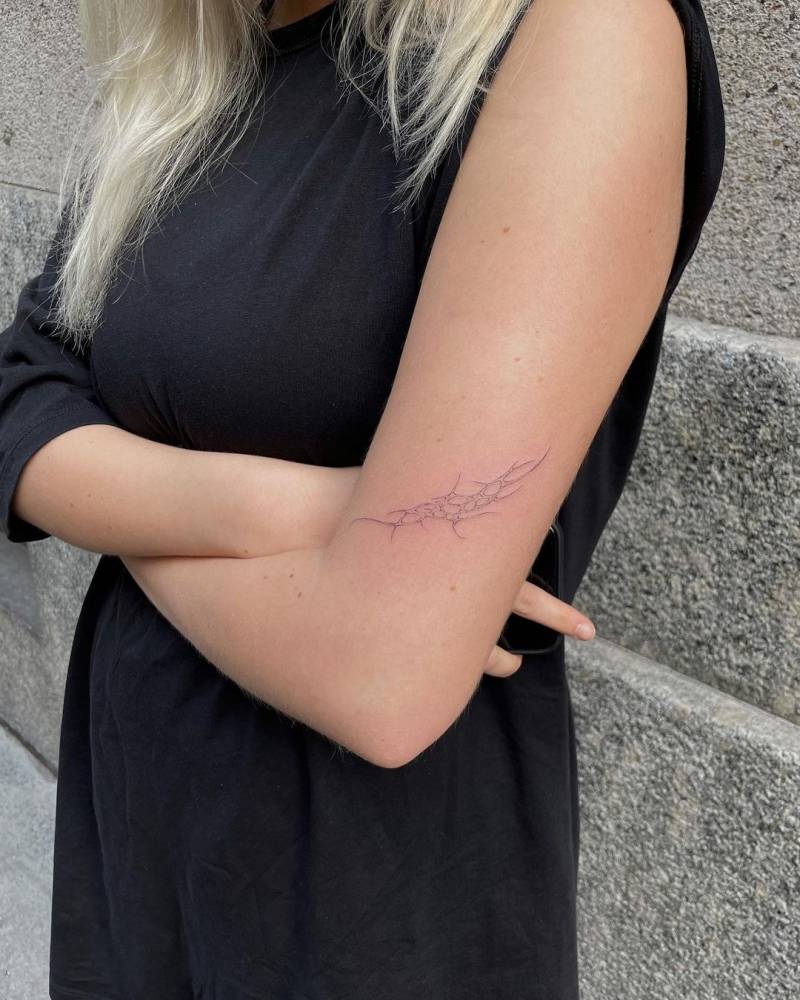 Single needle tribal tattoo on the upper arm.