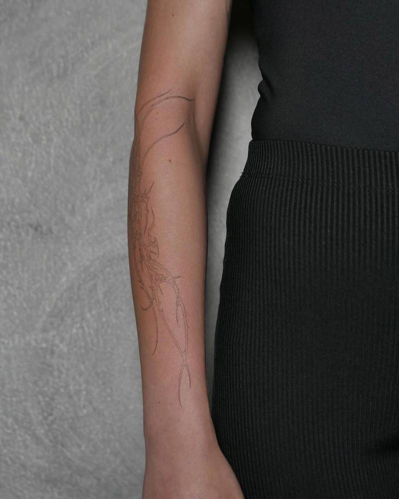 Single needle tribal tattoo on the forearm.