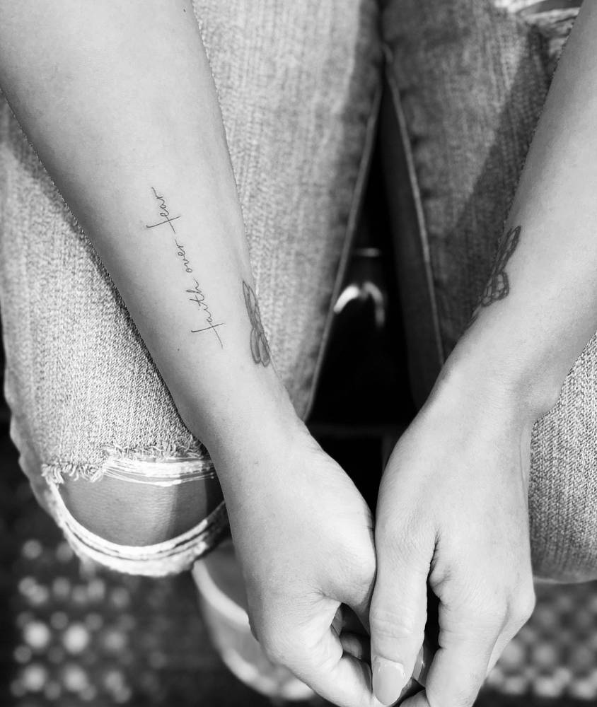 "Faith over fear" lettering tattoo on the wrist.