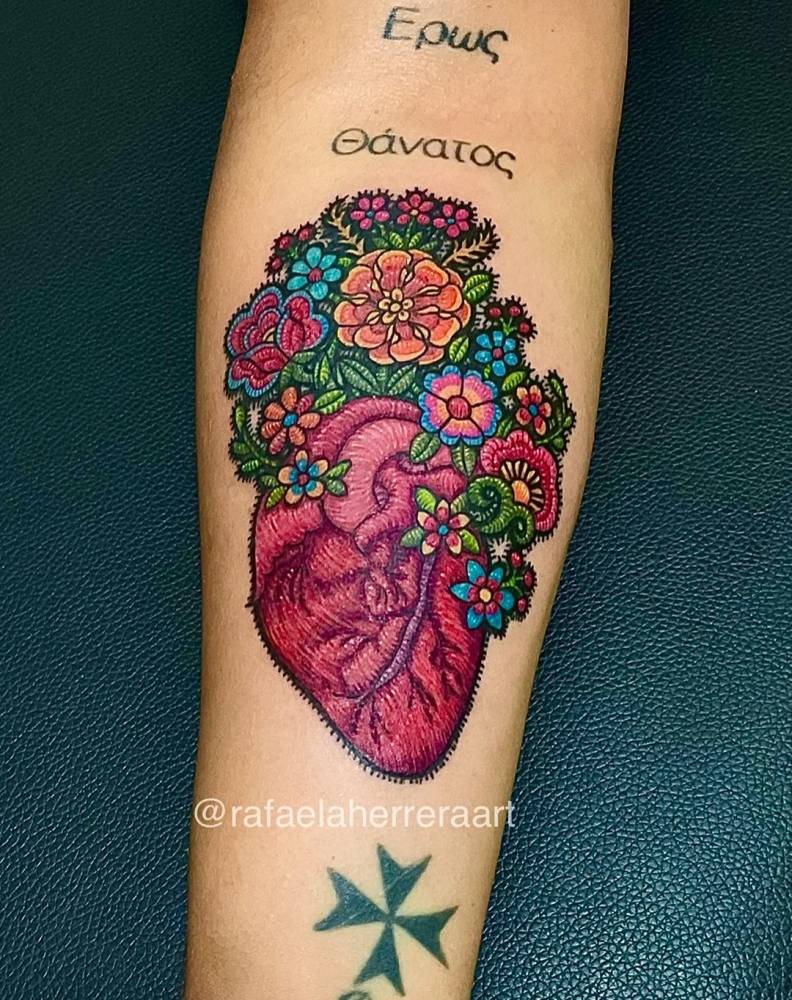 Anatomical heart and flowers tattoo located on the inner forearm, embroidery style.