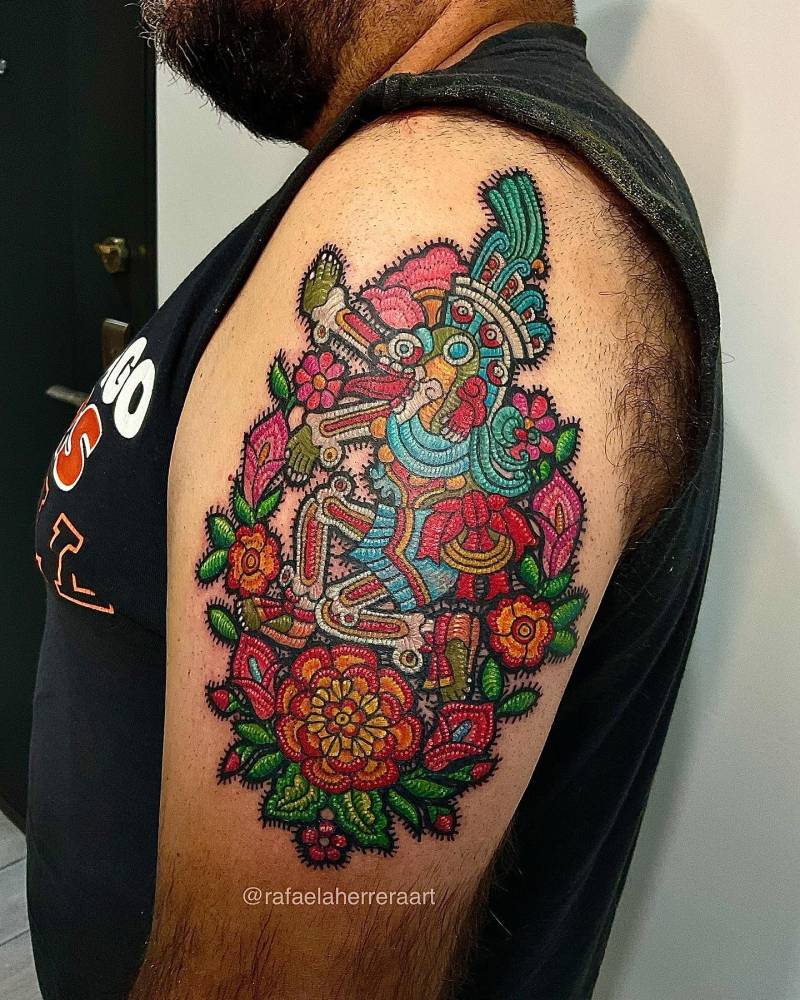 Mictlantecutli tattoo located on the upper arm, embroidery style.