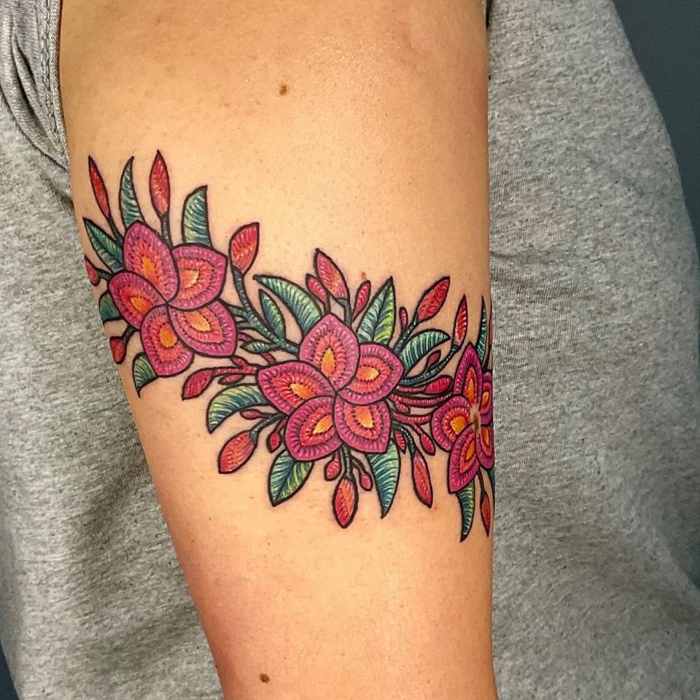Embroidery style plumeria flowers tattoo located on the upper arm.