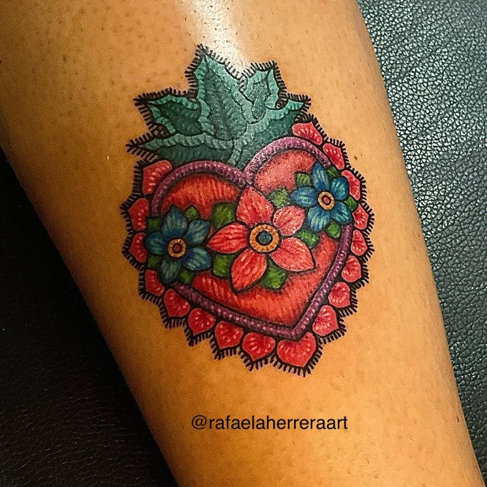 Flower heart tattoo in embroidery style located on the forearm.
