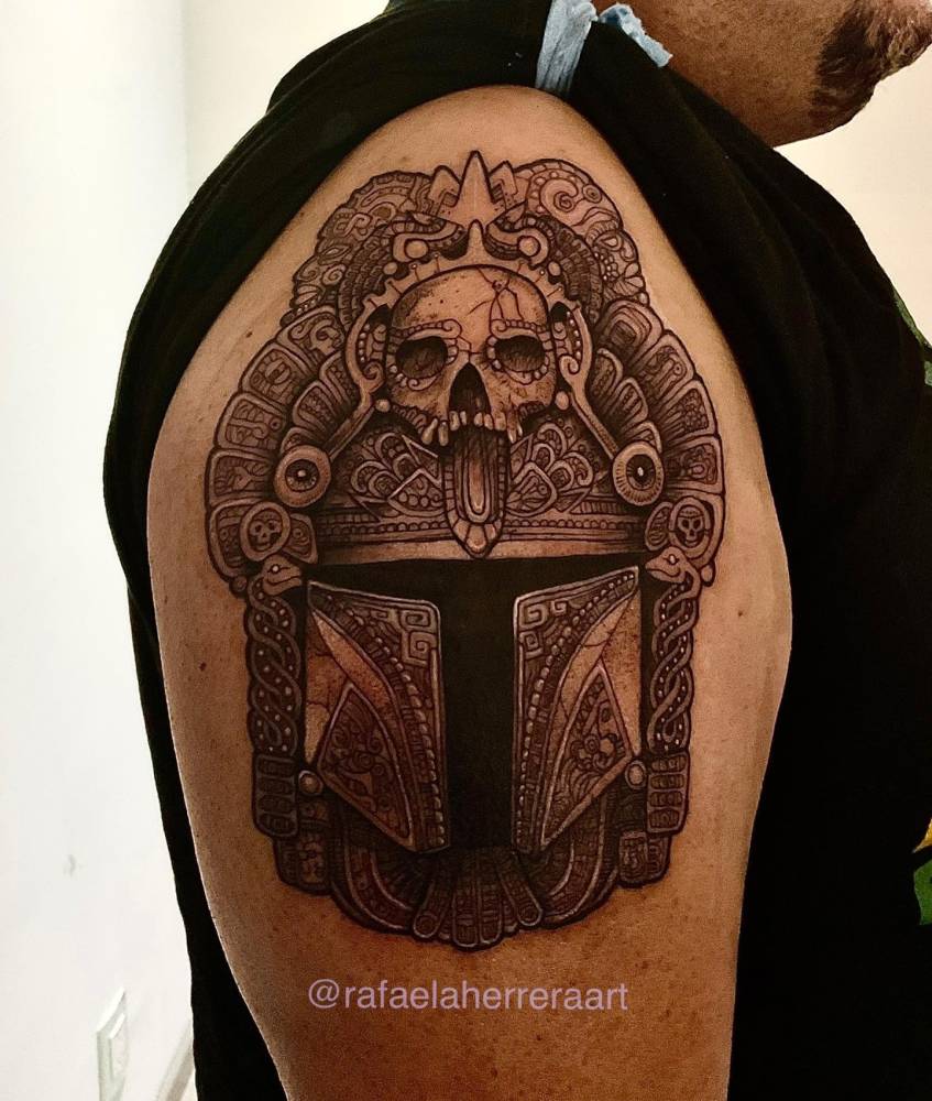 Mandalorian helmet tattoo in illustrative style placed on the upper arm.