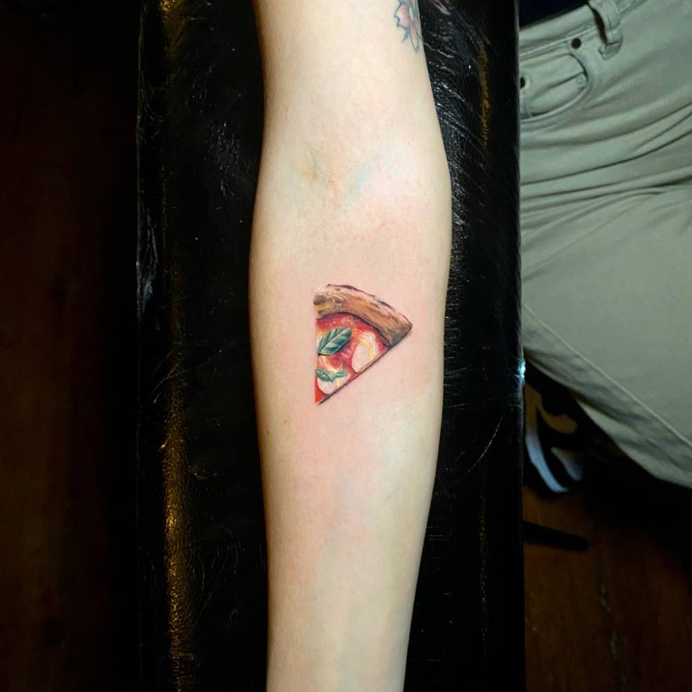 Margherita pizza tattoo located on the inner forearm, micro-realistic style.