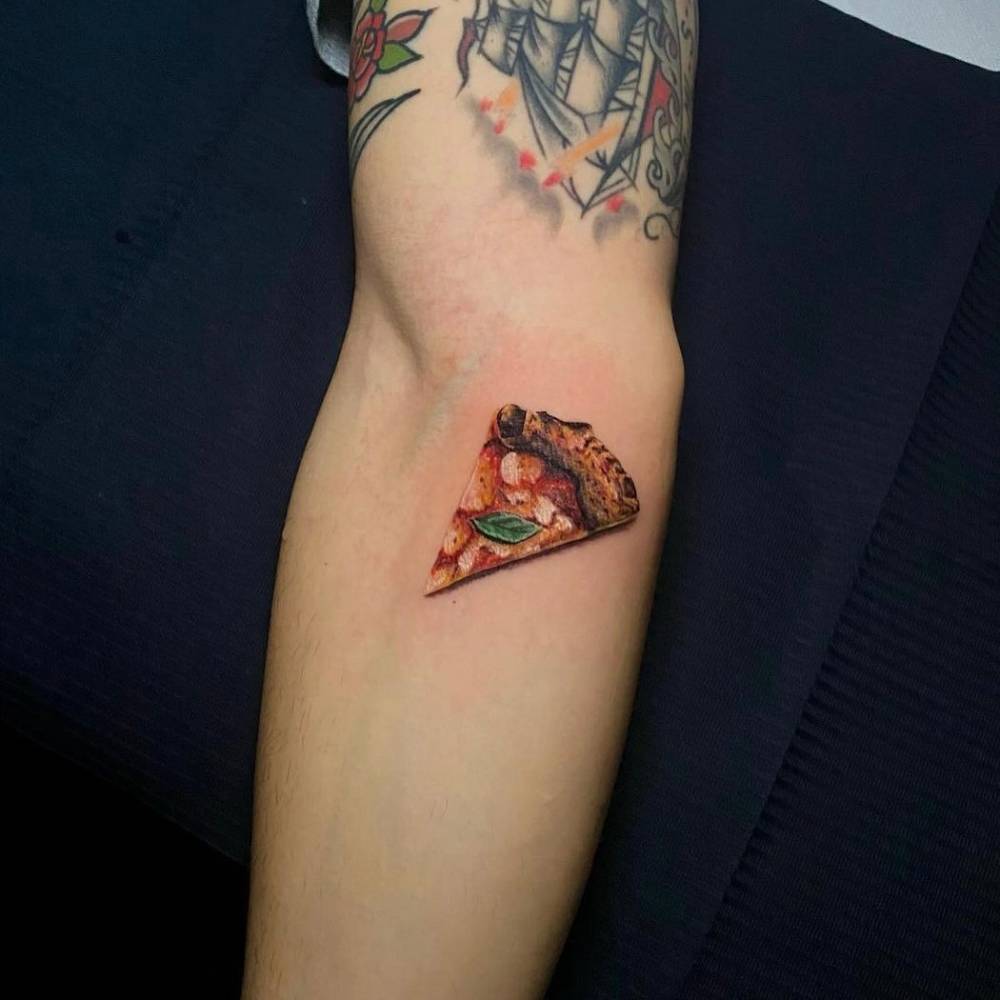 Margherita pizza tattoo located on the inner forearm, micro-realistic style.
