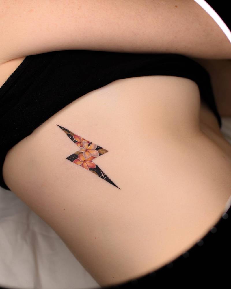 Lightning bolt and plumeria tattoo located on the side boob.