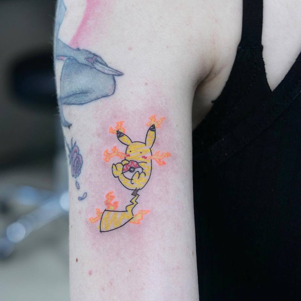 Cute Pikachu tattoo located on the upper arm, cartoon style.