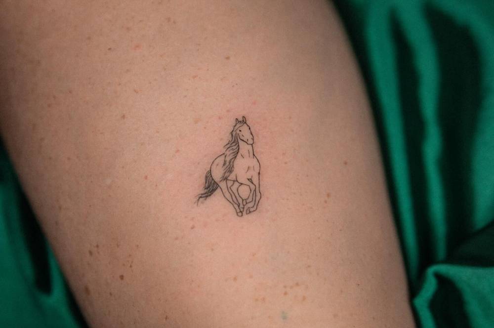Fine line style horse tattoo located on the calf.