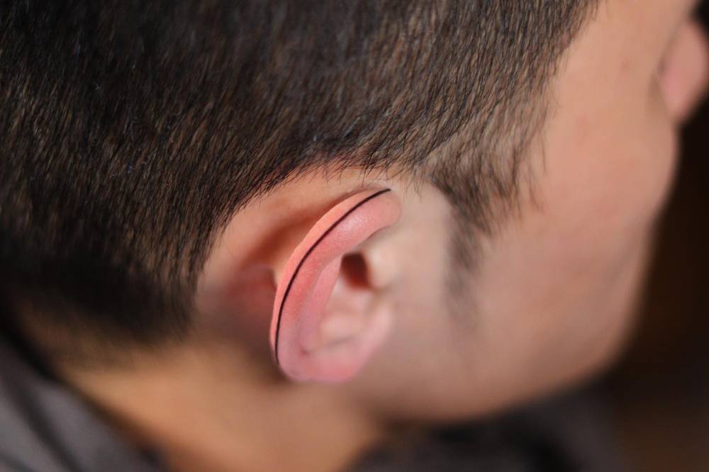 Minimalistic line tattoo located on the ear.