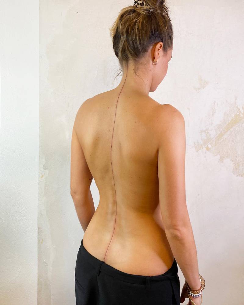 Minimalistic line tattoo located on the spine.
