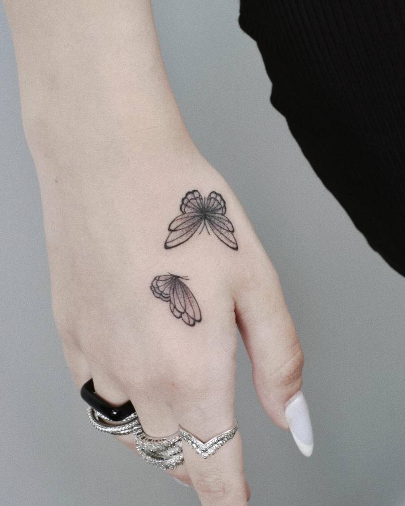 Illustrative style butterfly couple tattoo located on the hand.