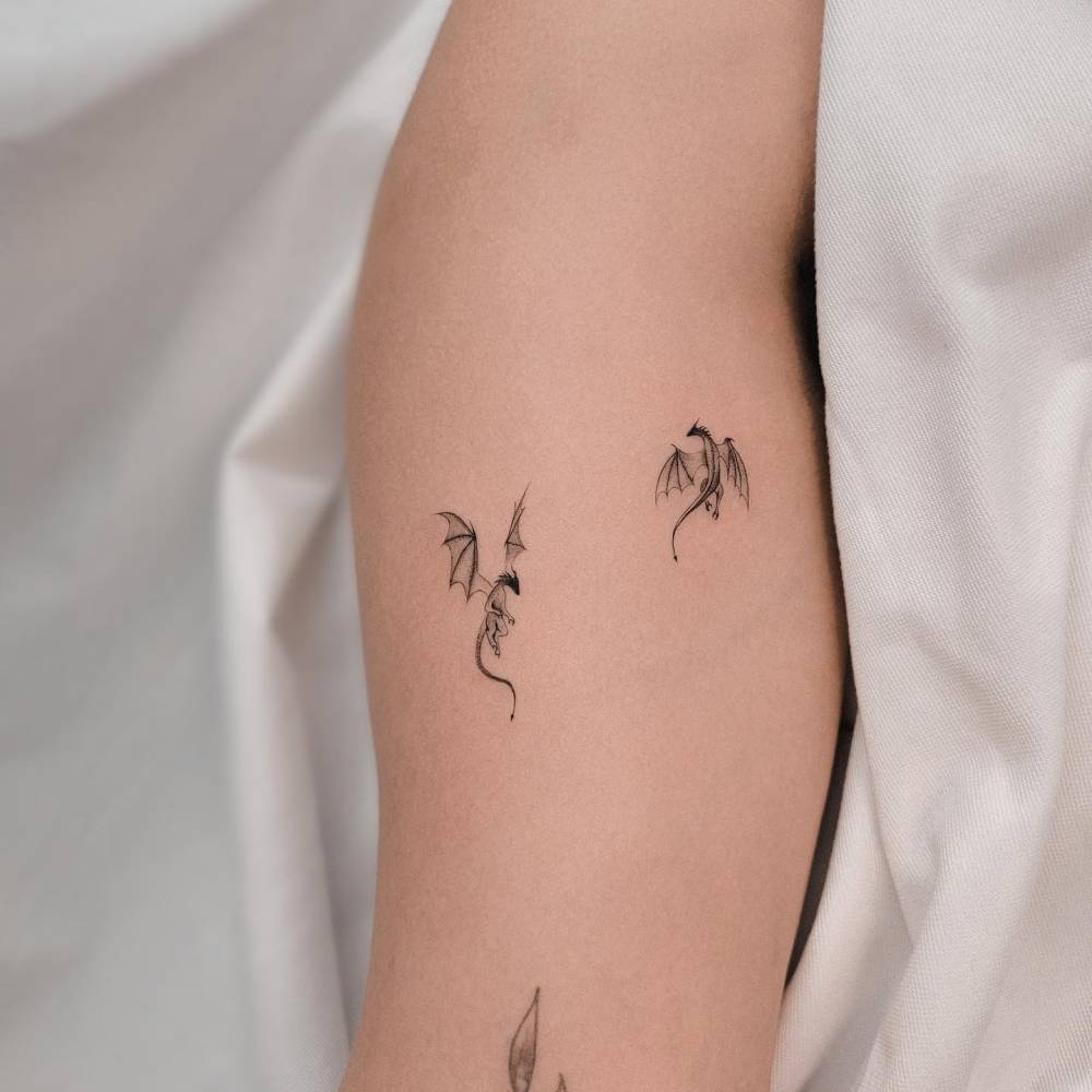 Illustrative style little dragons tattoo located on the bicep.