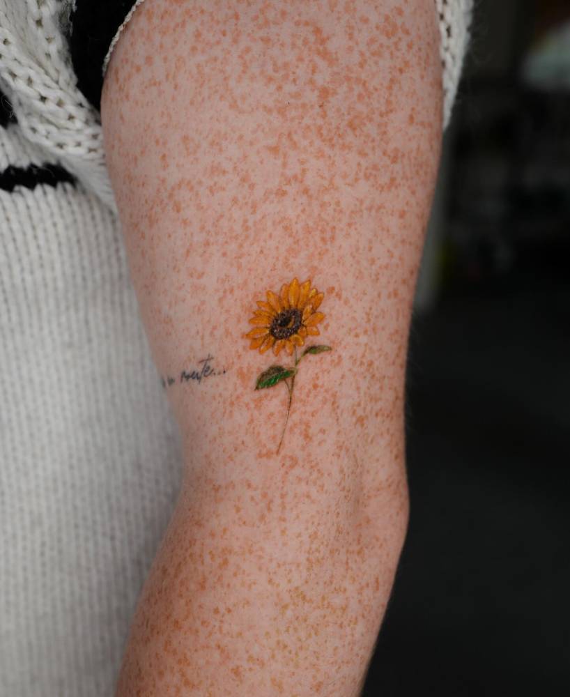 Watercolor style sunflower tattoo located on the upper arm.