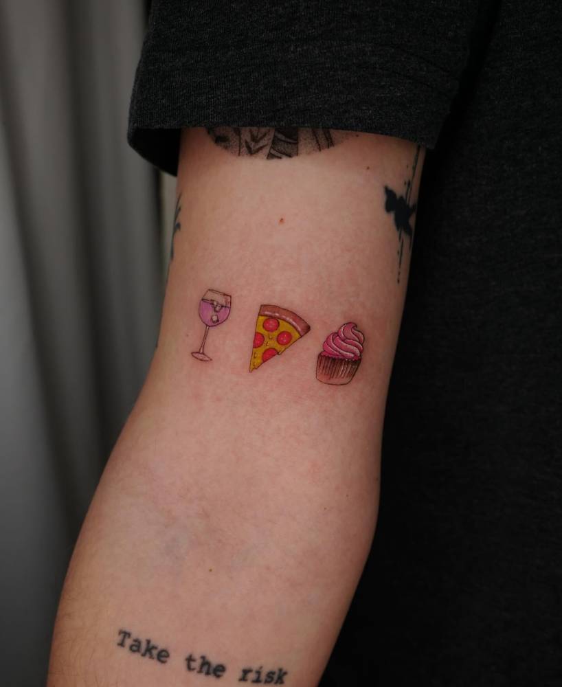 Illustrative style drink, pizza and cupcake tattoo located on the bicep.