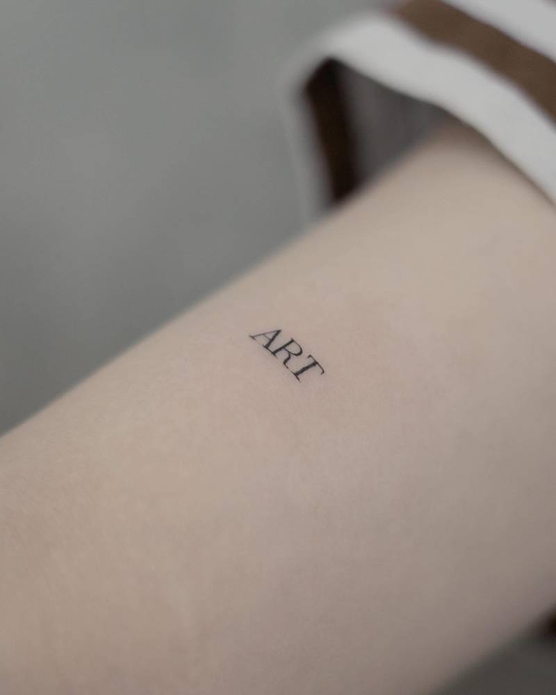 Lettering tattoo of the word "art" located on the bicep.