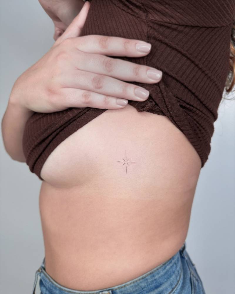 Fine line style north star tattoo placed on the side boob.