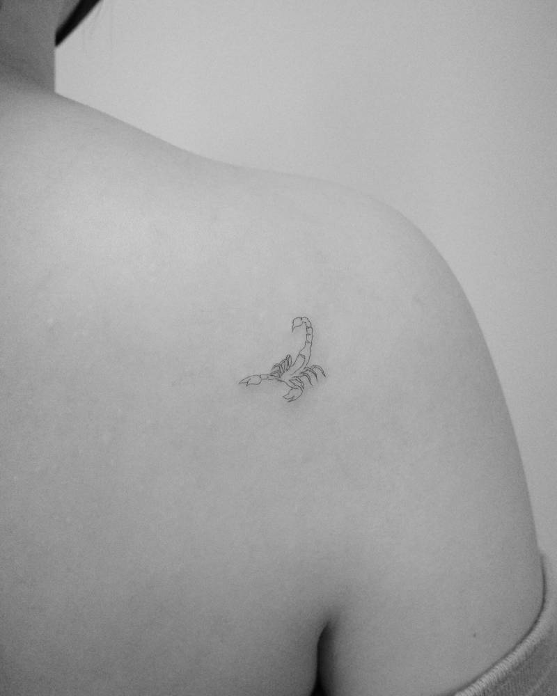 Minimalistic fine line scorpion tattoo located on the shoulder blade.