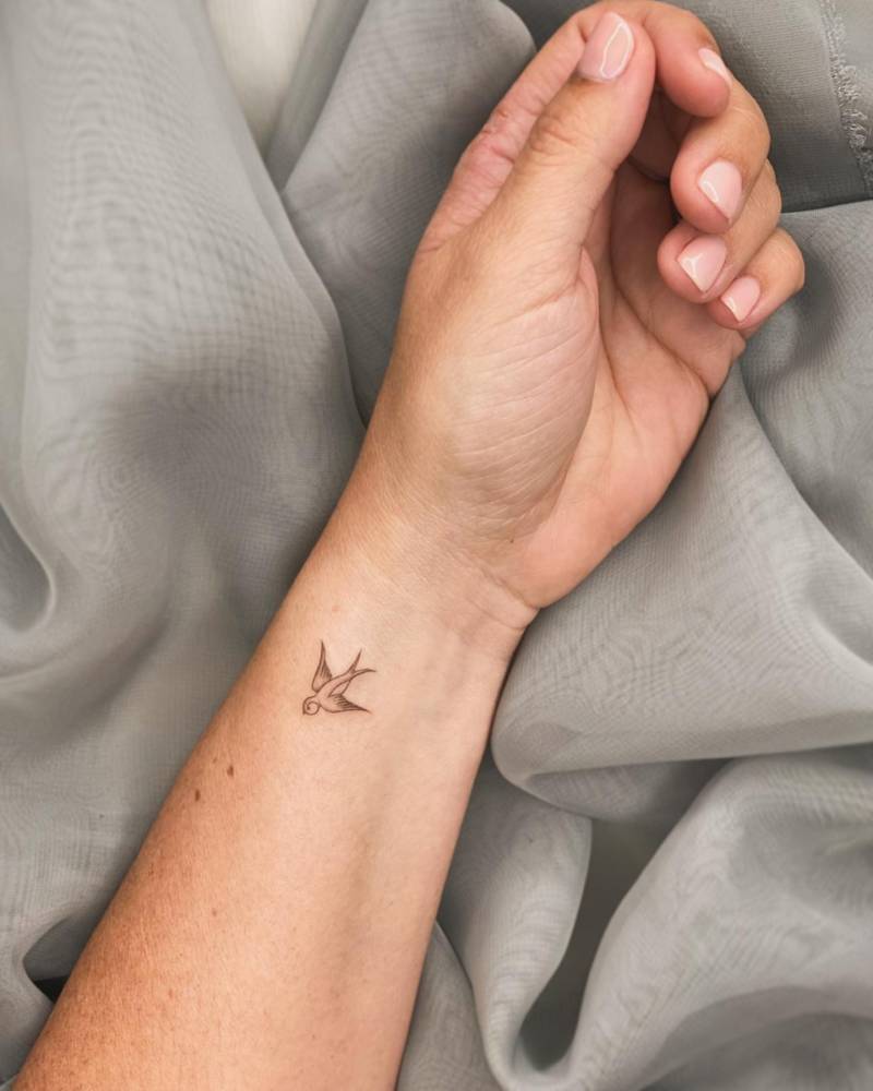Minimalistic style swallow tattoo located on the wrist.