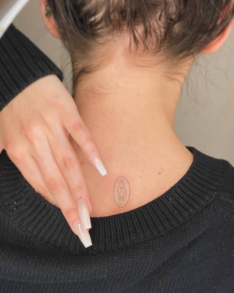 Minimalistic style Virgin Mary tattoo placed on the upper back.