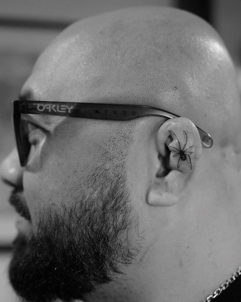 Single needle spider tattoo located on the ear.