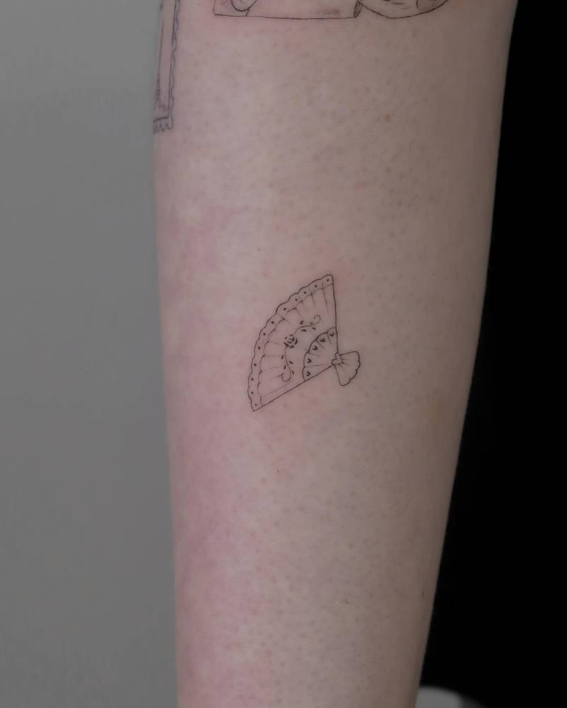 Fine line style hand fan tattoo located on the forearm.