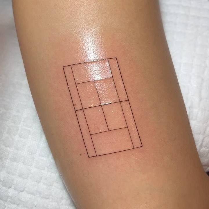Fine line style tennis court tattoo located on the tricep.