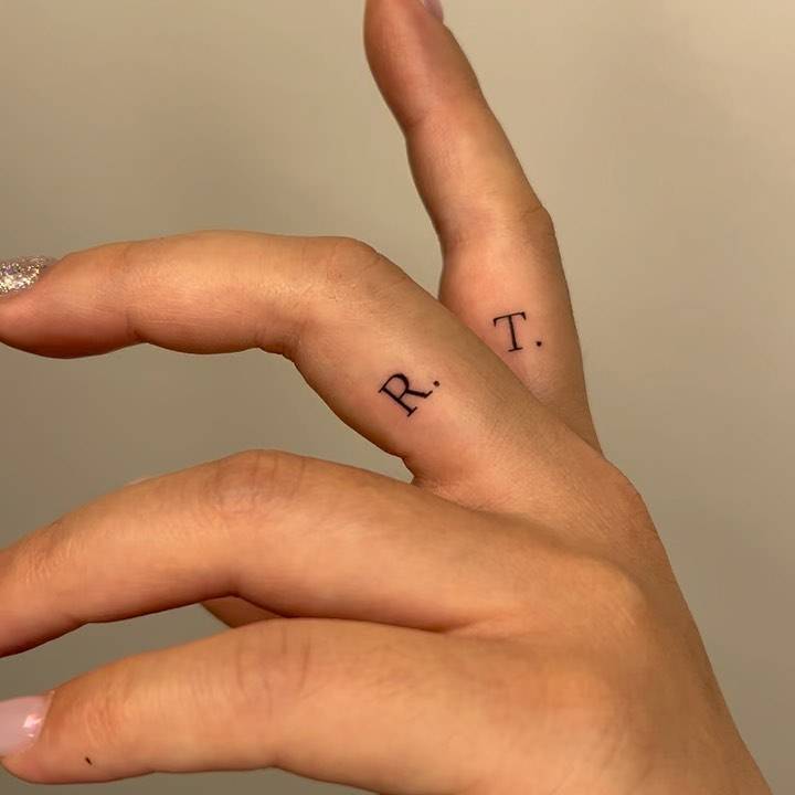 Letters "R" and "T" tattooed on the fingers.