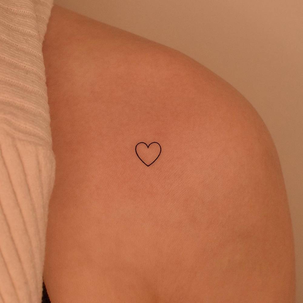 Minimalistic tiny heart tattoo placed on the shoulder.