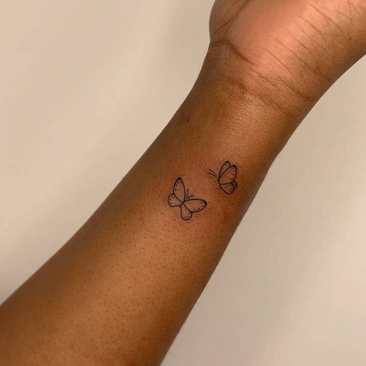 Minimalistic style butterfly couple tattoo located on the wrist.