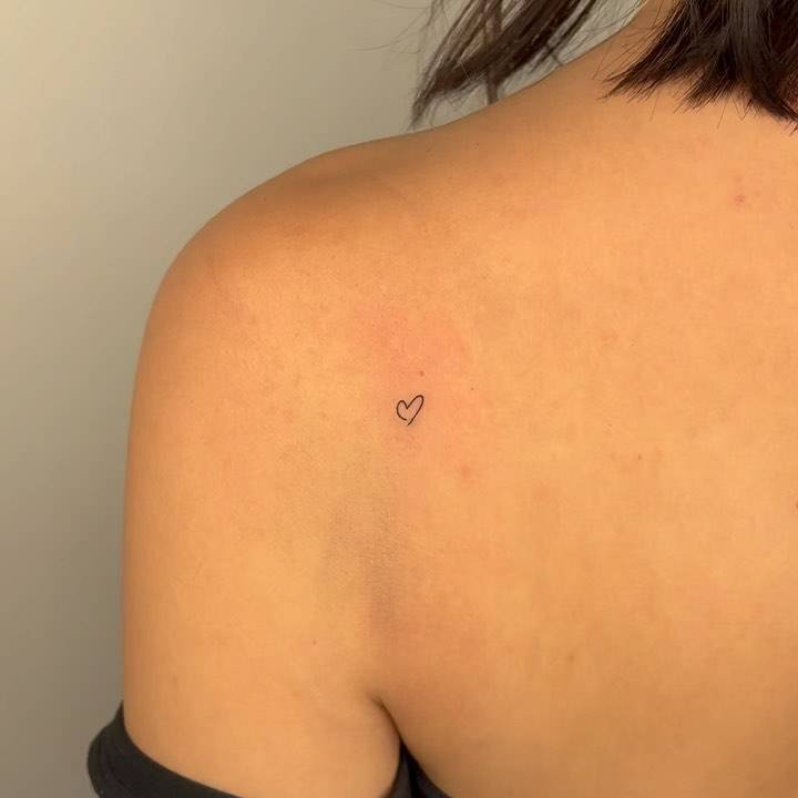 Tiny minimalistic heart tattooed on the shoulder blade.