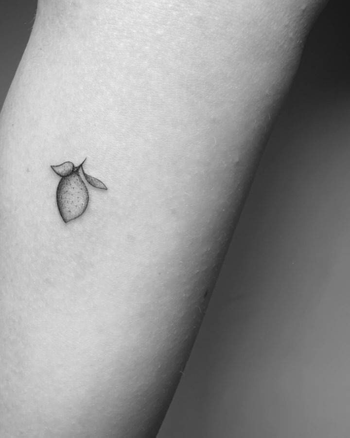 Tiny lemon tattoo in illustrative style located on the inner forearm.