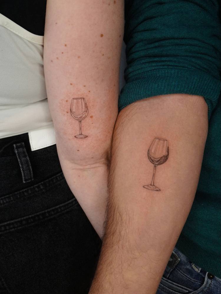 Matching wine glass tattoo in illustrative style for couple.