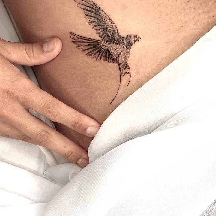 Micro-realistic swallow tattoo on the waist.