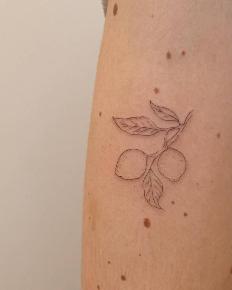 Fine line style lemons tattoo located on the upper arm.