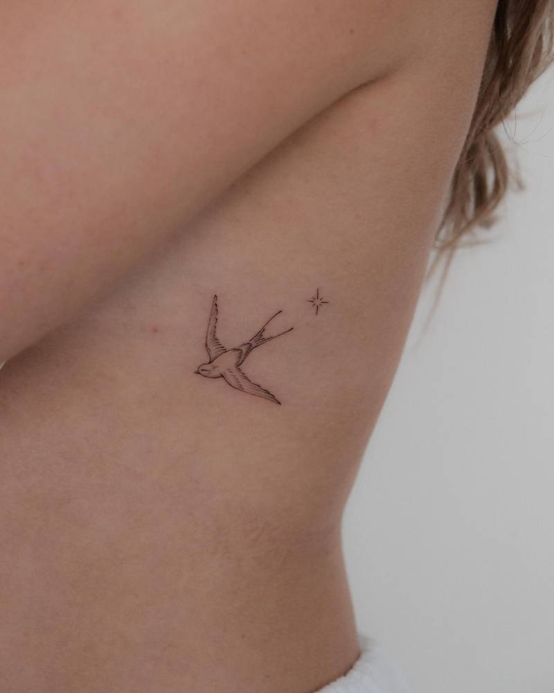 Fine line style tattoo of a swallow placed on the rib.