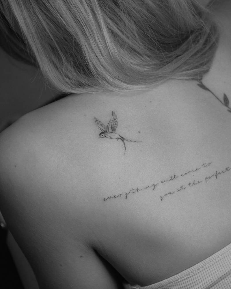 Illustrative style swallow and lettering tattoo located on the shoulder blade.